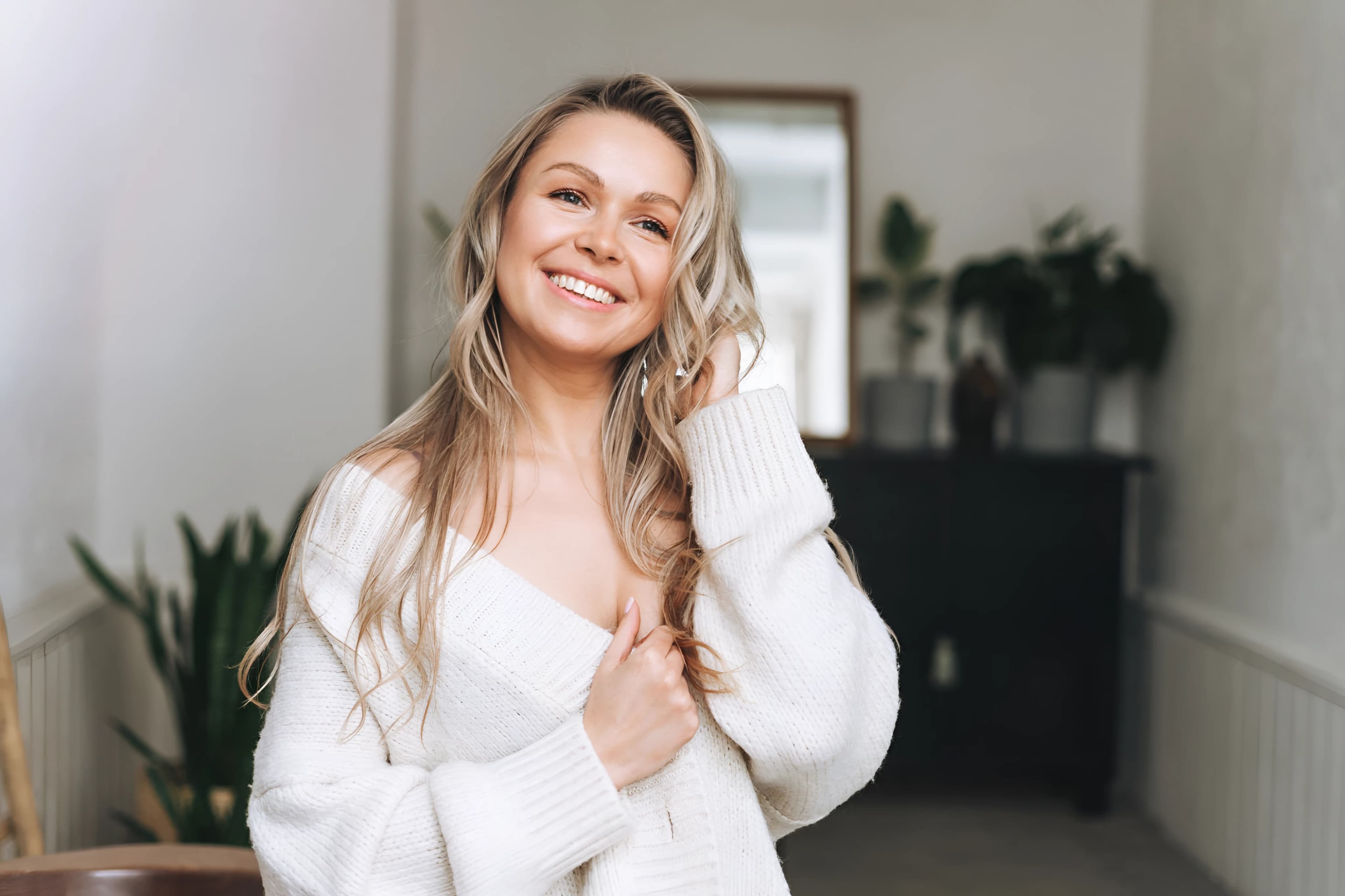 Smiling woman in a white sweater in a bright hallway