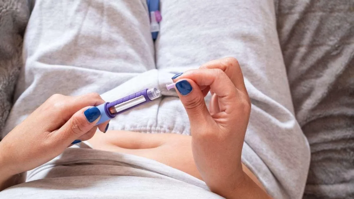 Mujer aplicándose una pluma de inyección de bienestar en el abdomen